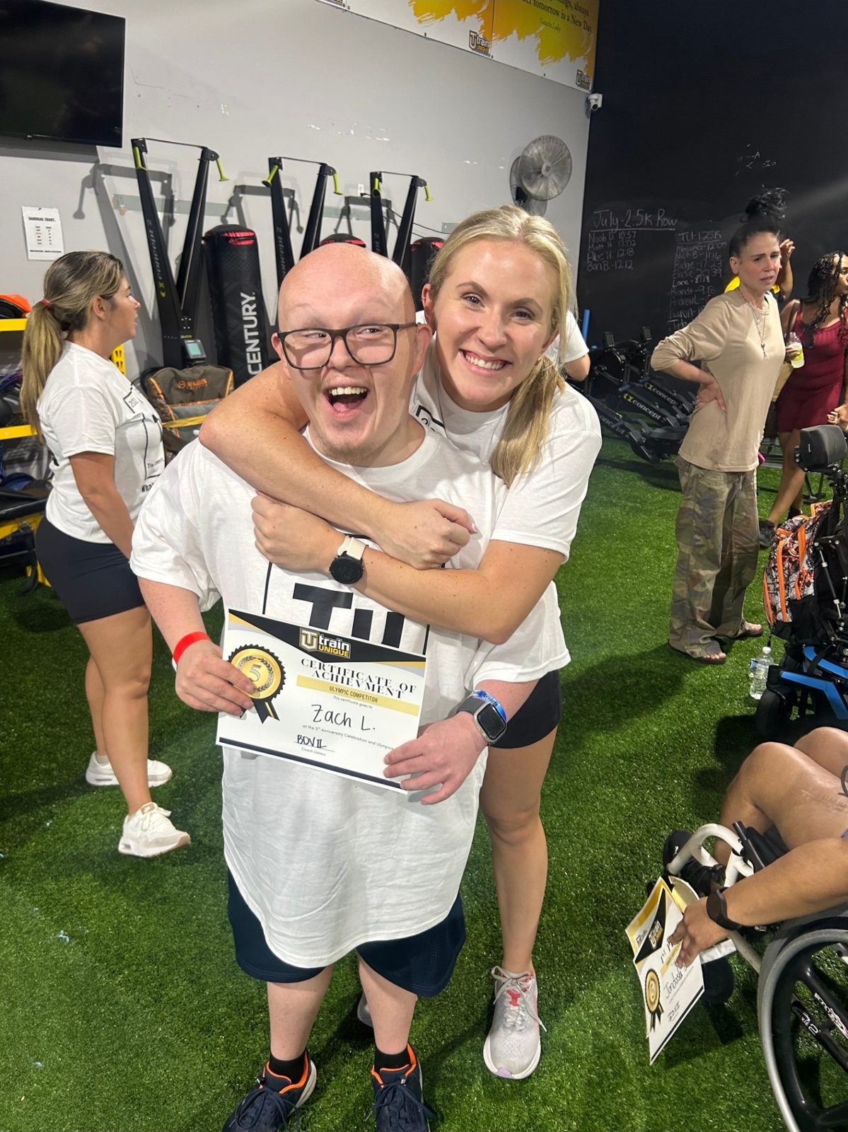 Linden hugging one of her athletes as he holds up his Ulympics certificate