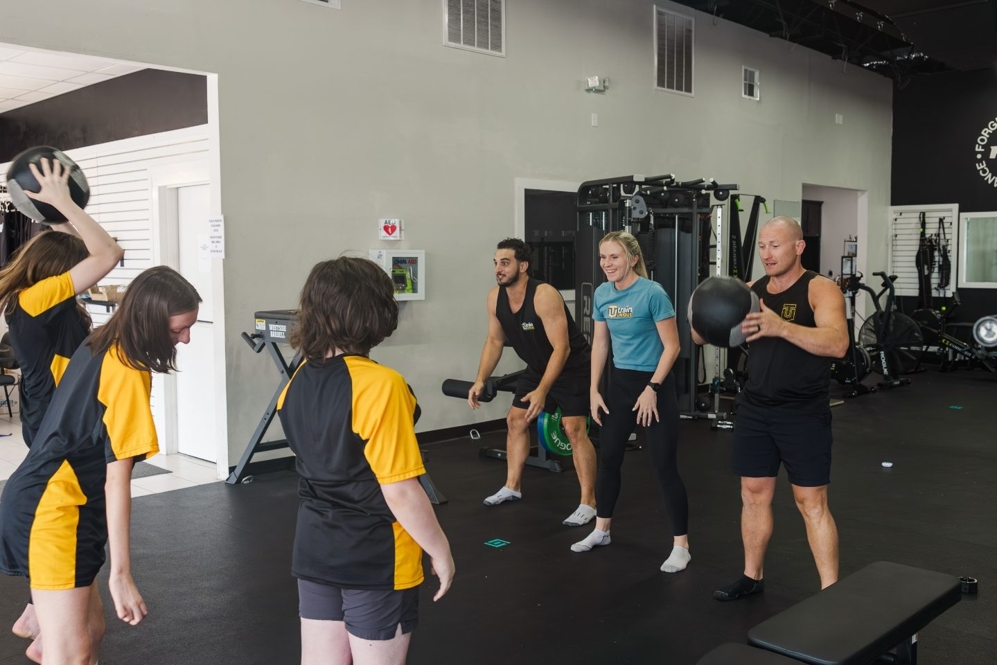 Linden and two coaches running a med ball drill with young athletes