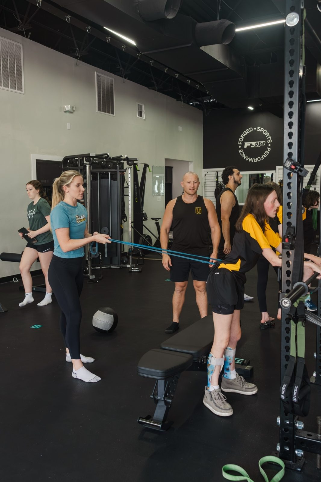 Linden holding the resistance band for an athlete training at the bench