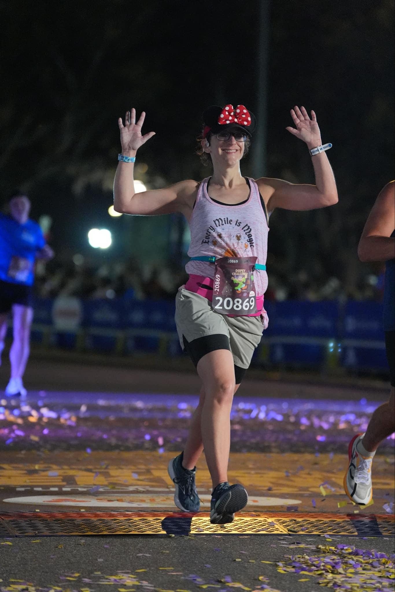 Elizabeth crossing the marathon finish line with both hands in the air