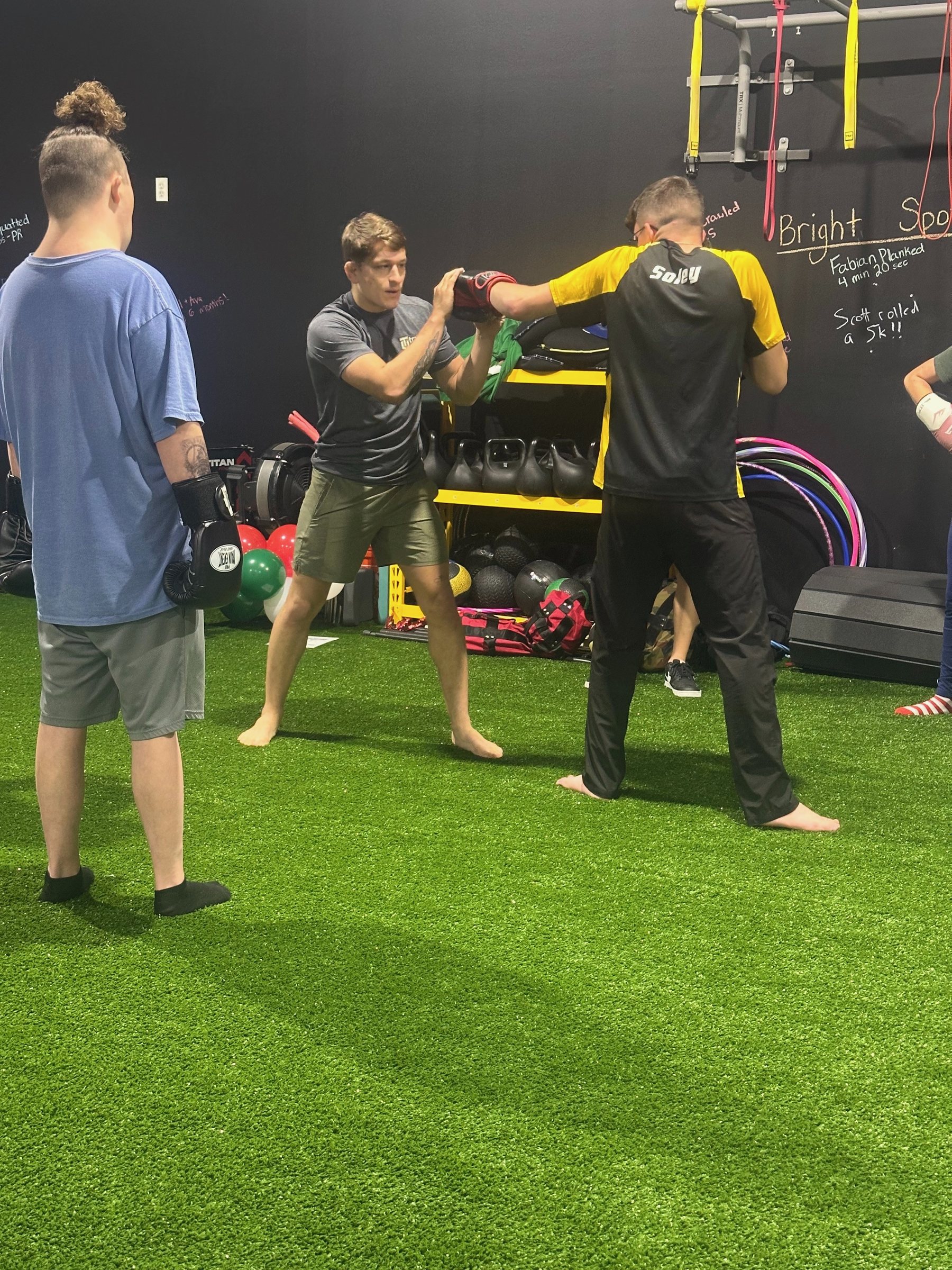A coach holding the focus mitt while an athlete throws a punch