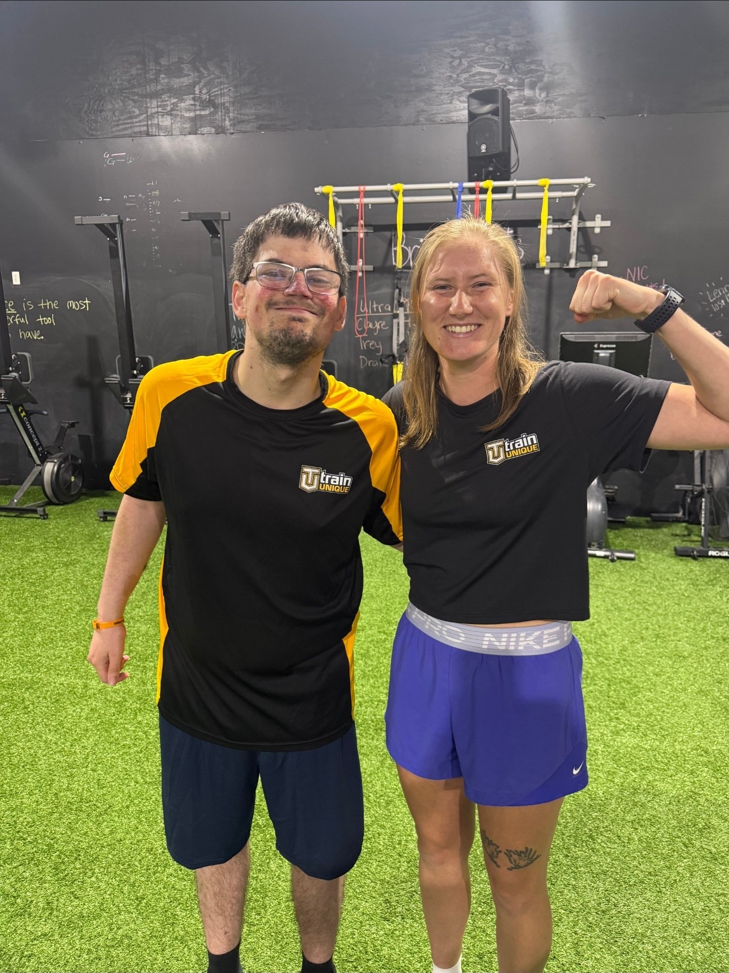 Shannon flexing next to one of her athletes in matching Train Unique shirts