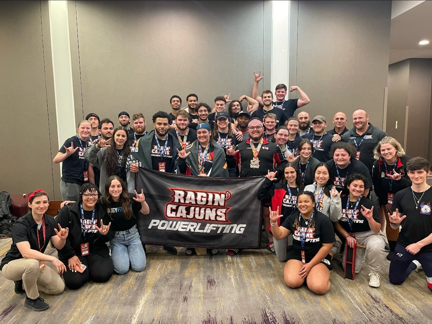The Ragin' Cajuns powerlifting team posed around their banner