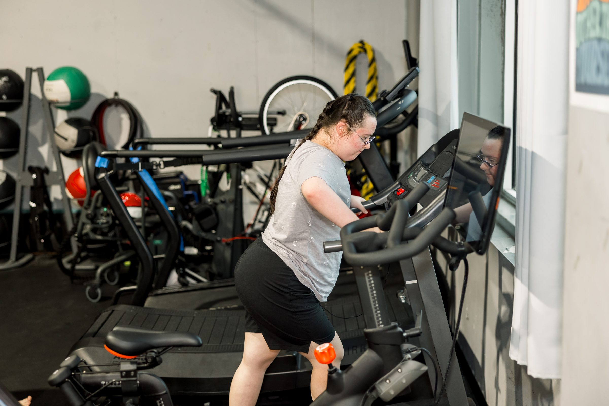An athlete on the adaptive bike with her coach nearby