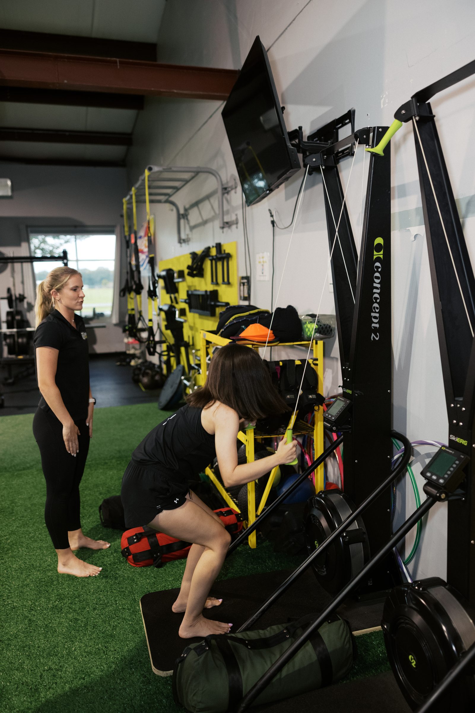 An athlete rowing on the TRX with her coach