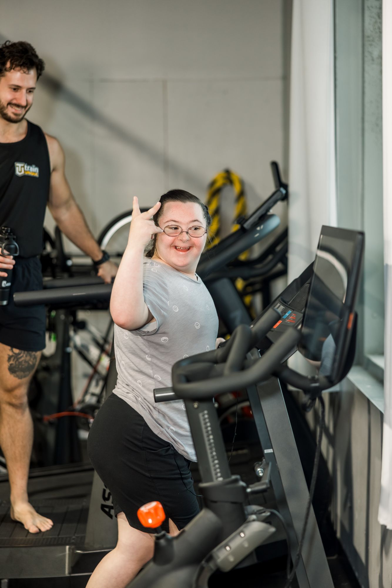 An athlete on the bike giving a thumbs-up, coach behind