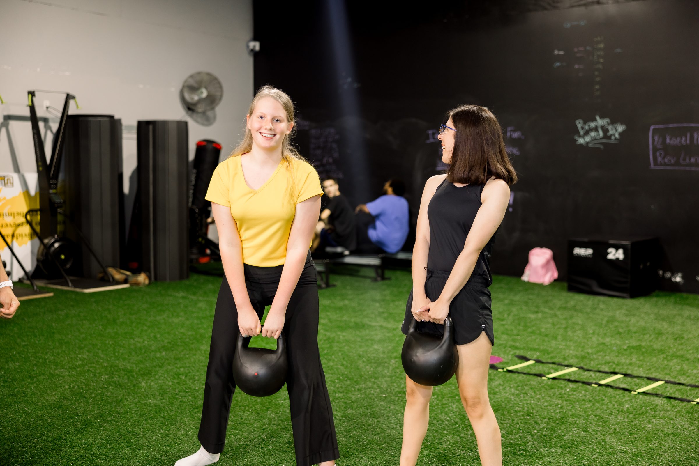 Two athletes working kettlebells side by side