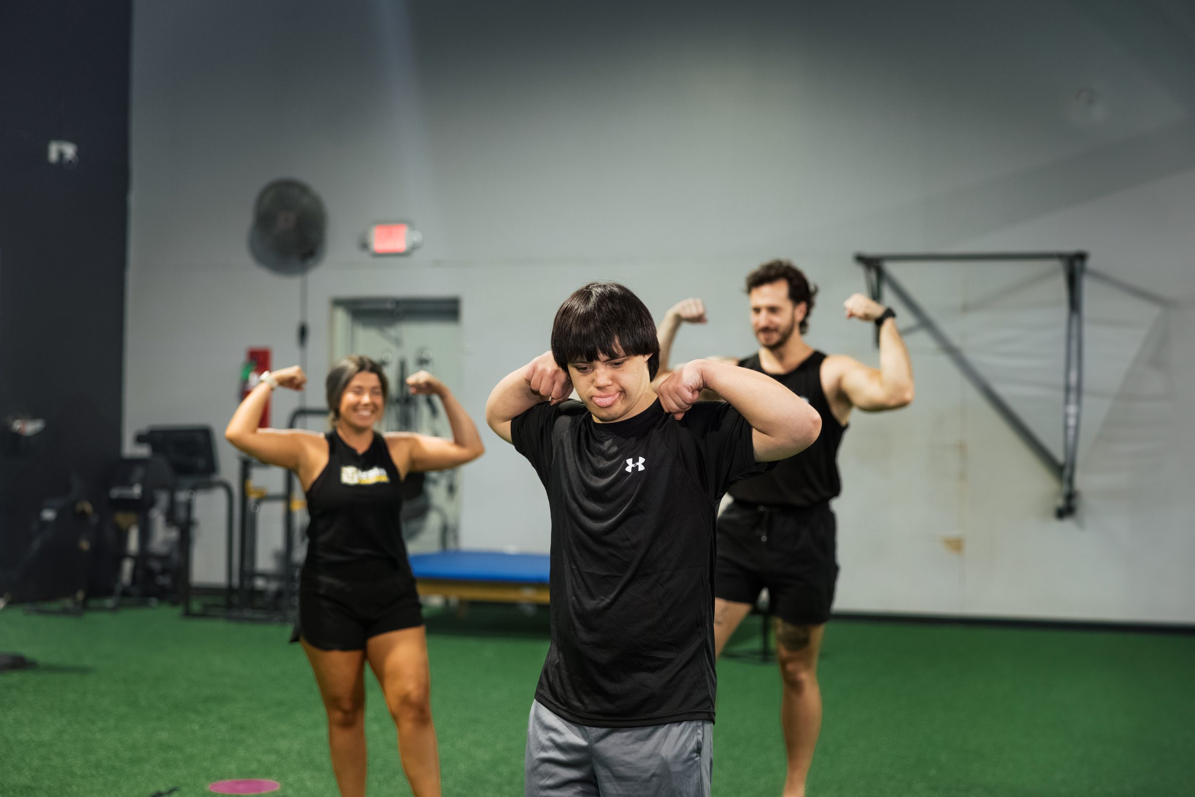 Athletes and coaches flexing together on the turf