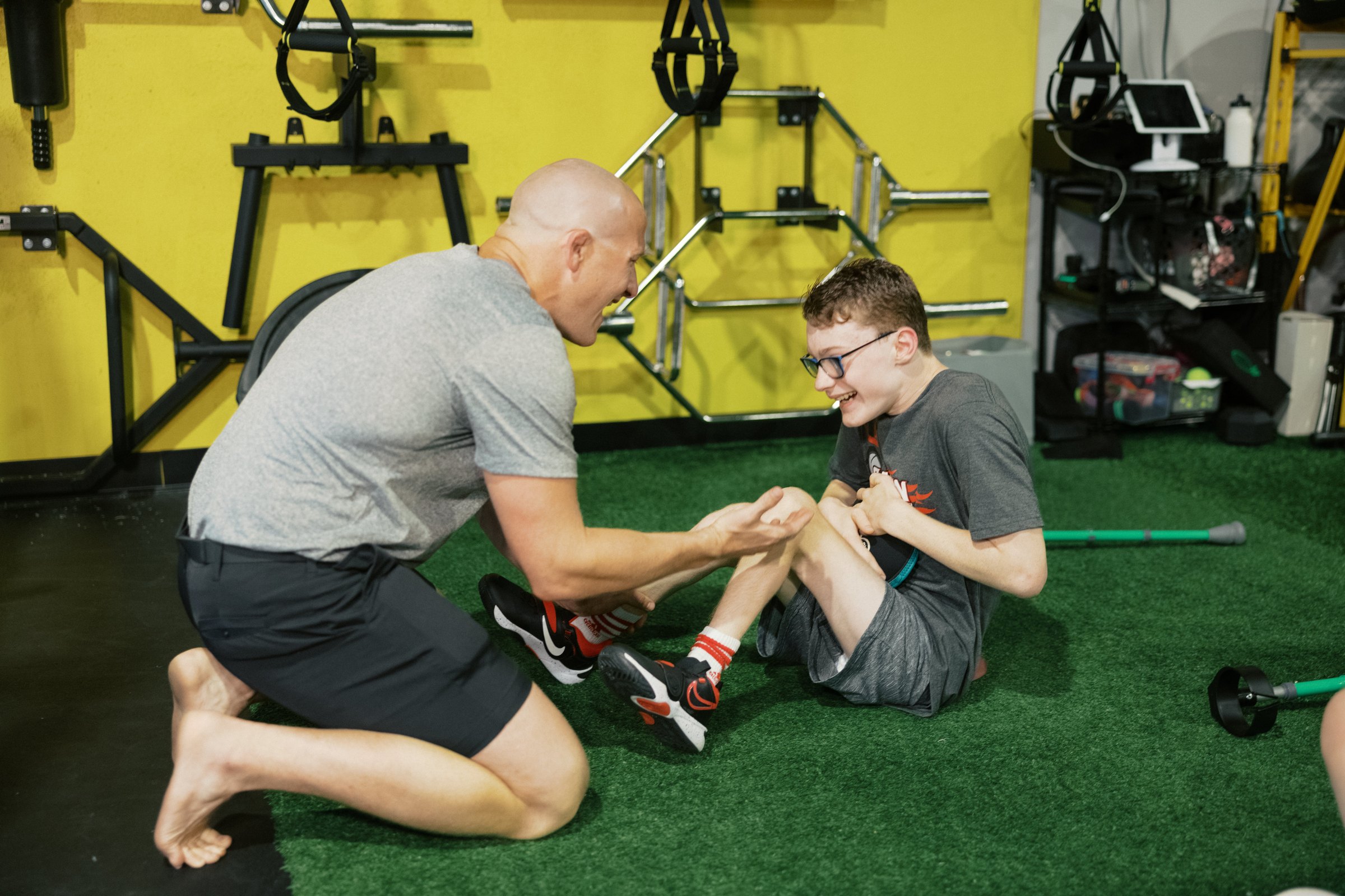 A coach on the floor working a movement with an athlete