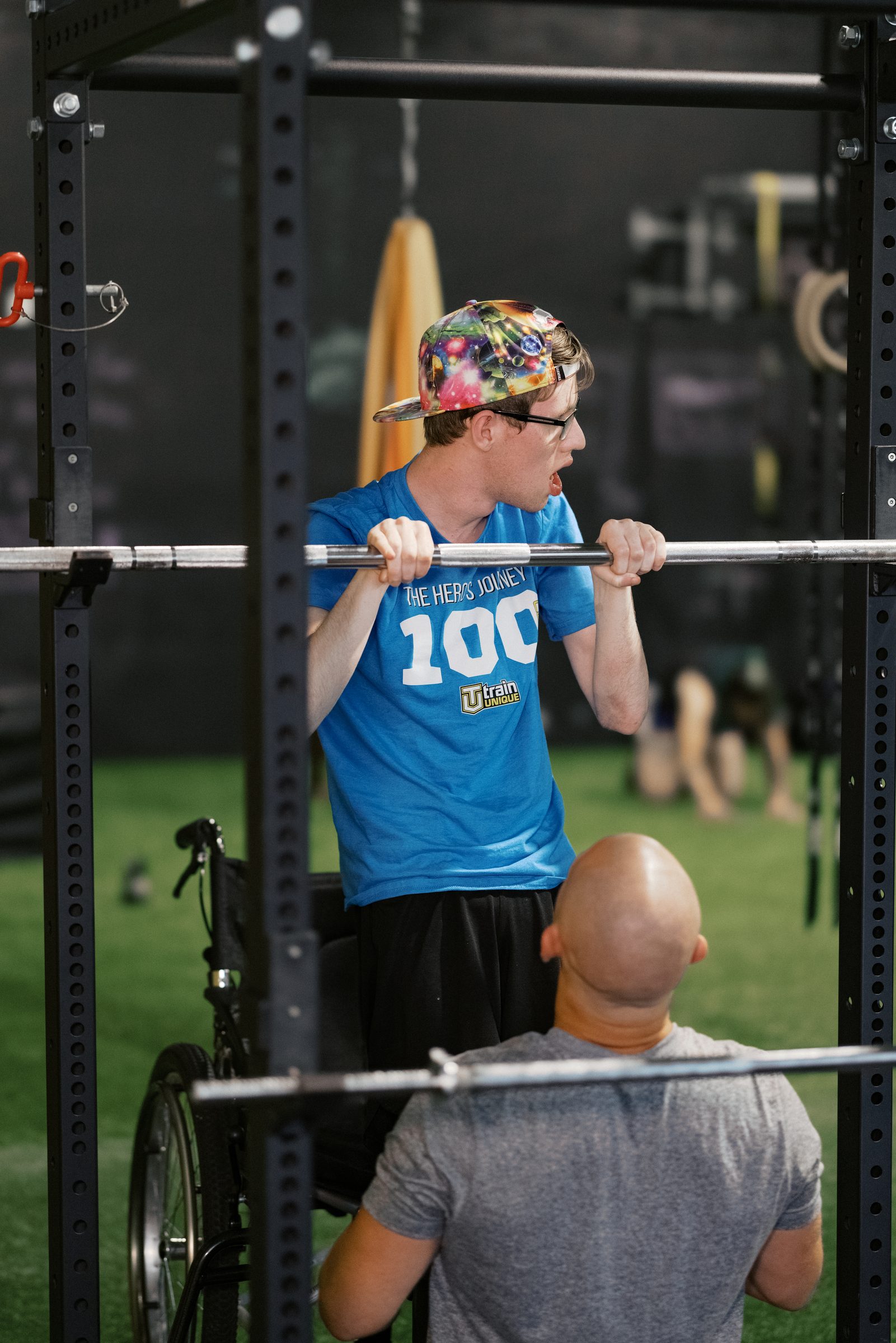 An athlete at the bar with his coach spotting from his wheelchair