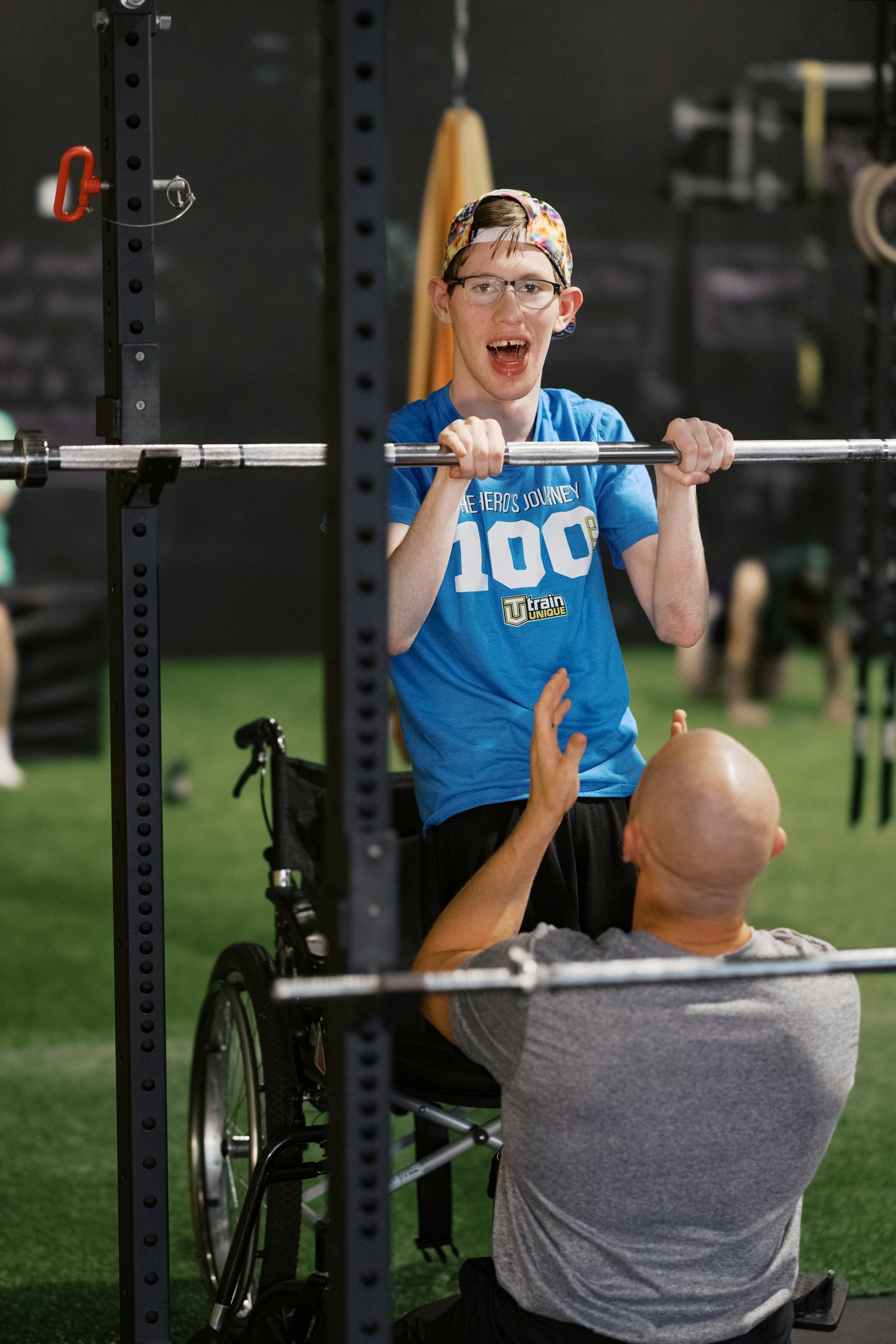 An athlete under the bar, coach kneeling beside him