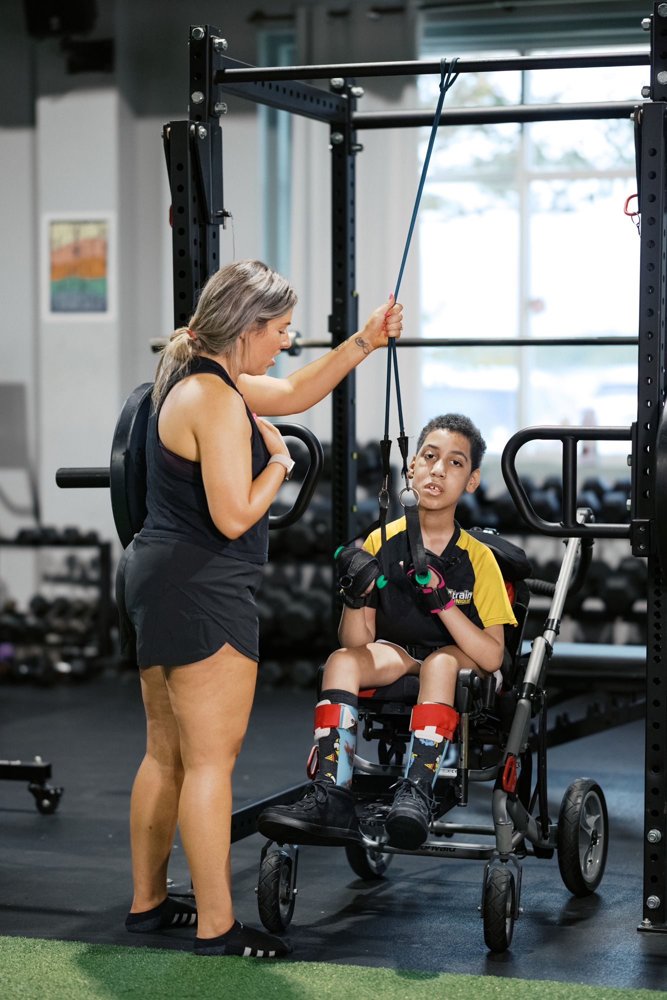An athlete in his chair working the cable, coach at the stack