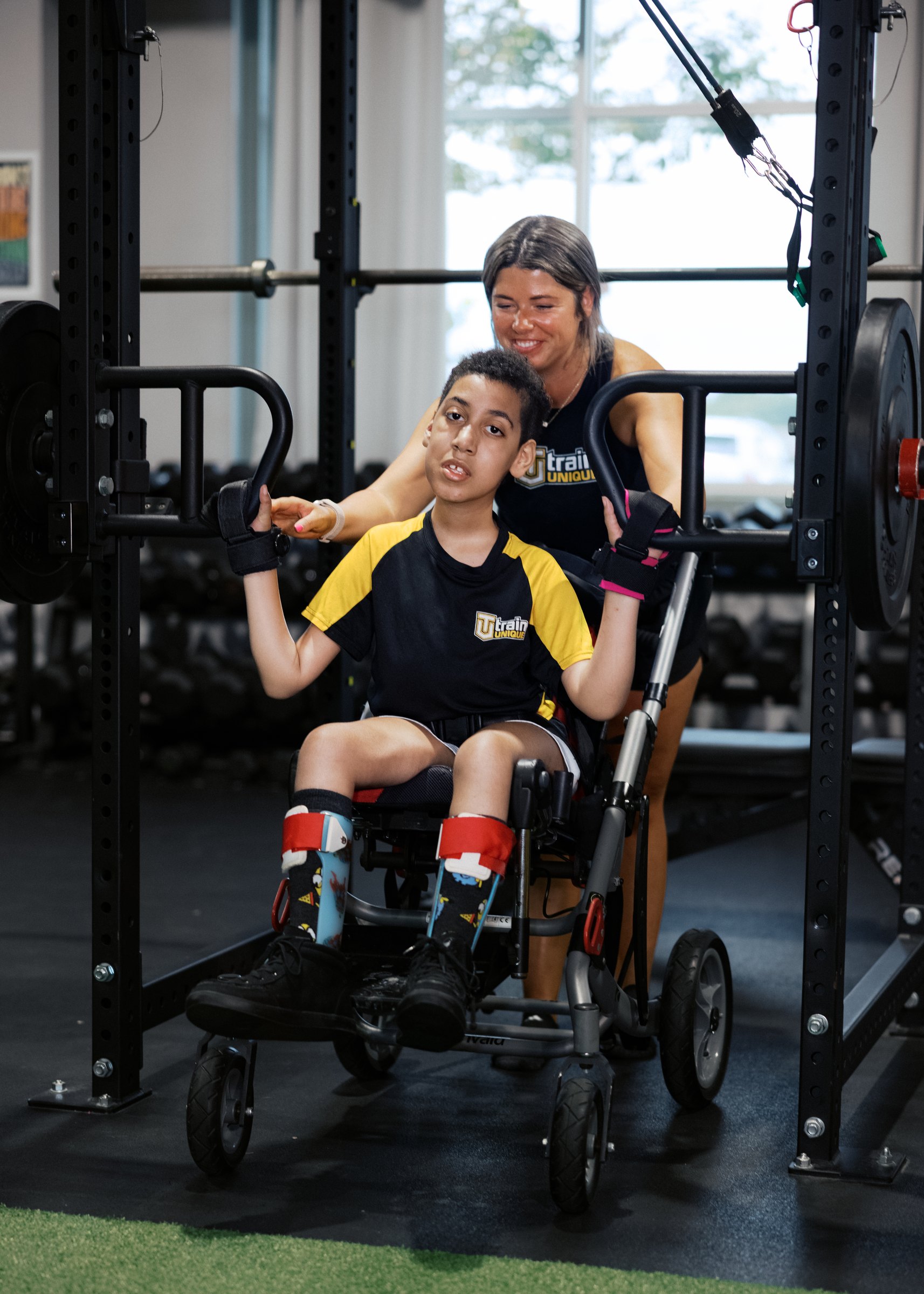 A coach guiding an athlete through a movement in a standing frame