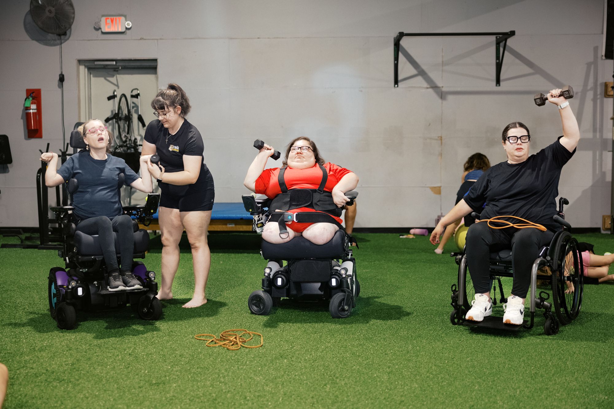 Athletes in their chairs pressing dumbbells with their coaches