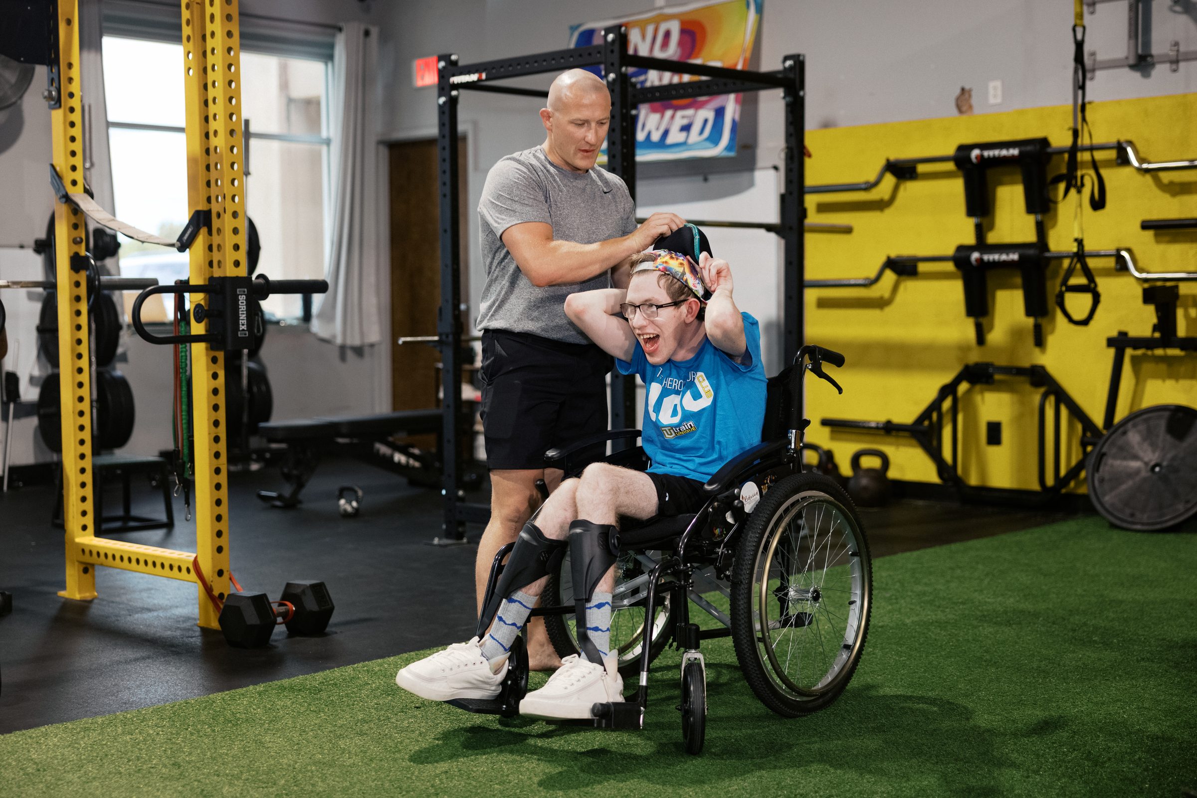 A coach working with an athlete at the rack beside his wheelchair